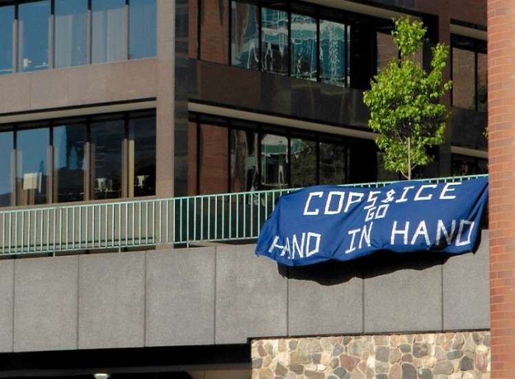 A banner saying "Cops and ICE Go Hand in Hand" hangs off the Calder Plaza right before Tuesday's City Commission Meeting.