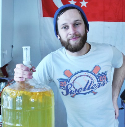 Dallas McCulloch poses beside a fresh blend of peach cider made in his home brewery. It has been converted into alcohol.