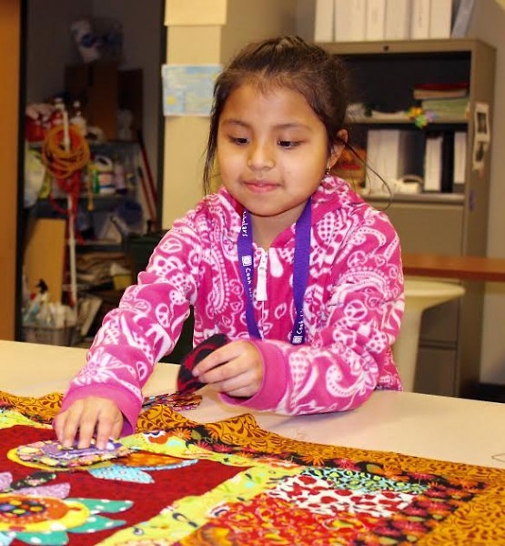 A student helping to make a quilt that was auctioned off at Día del Sol 2016