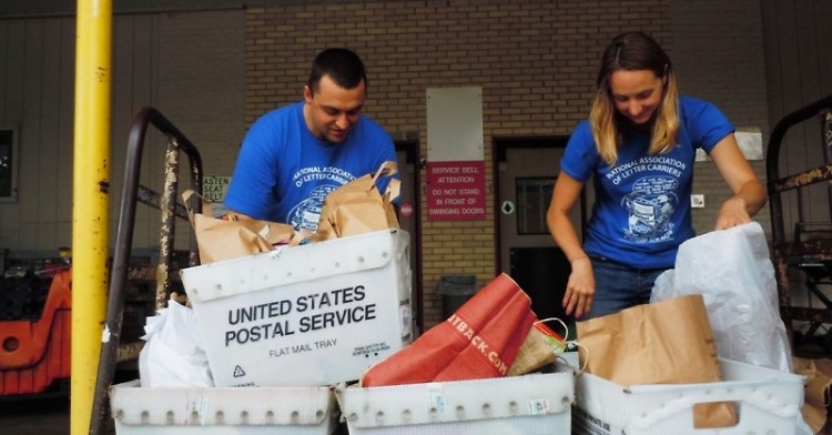 Feeding America West Michigan staff members Ryan VanMaldegen and Katie Auwers unpack Stamp Out Hunger donations, May 2015.