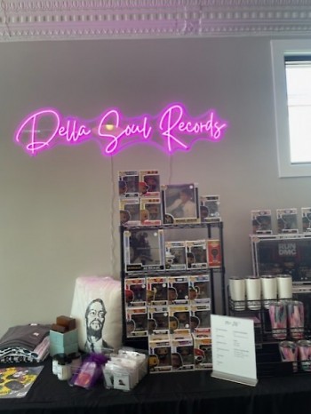 A purple Della Soul Records neon sign hangs over a display set out in the shop. 