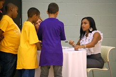 Dominique Dawes signing autographs for Club members and letting them hold her Olympic gold medal.