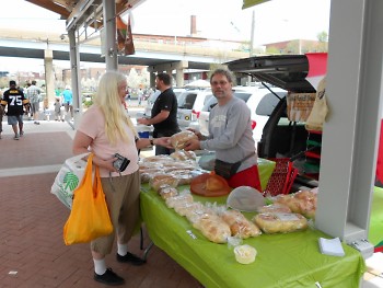 Customer Kathy McNamara purchases bread from local vendor Ric Gajewski