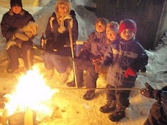 children warm up at the campfire in Dufferin Park in the city of Toronto