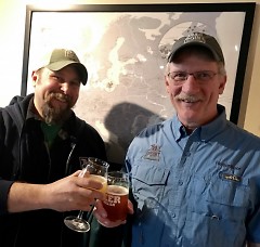 Jeff Knoblock (L) and Gary Evans, owner and head brewer, respectively, of Trail Point Brewing, toast with a glass of their beer.