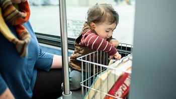 A child chooses a book from the KDL Books on the Bus program rack.