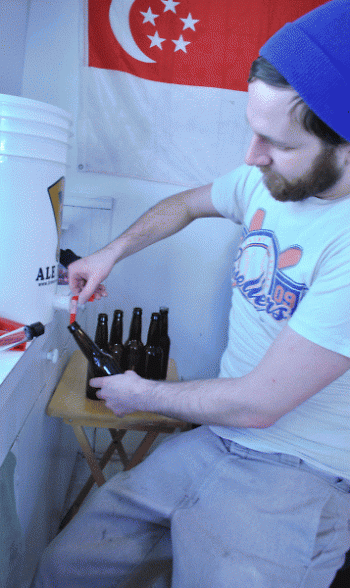 Dallas McCulloch fills a glass bottle with a fresh mixture of his own home-brewed beer.