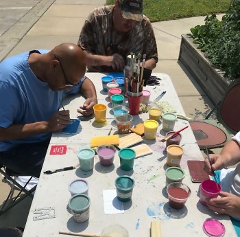Dwelling Place residents enjoy an outdoor painting activity to beautify their community garden downtown.