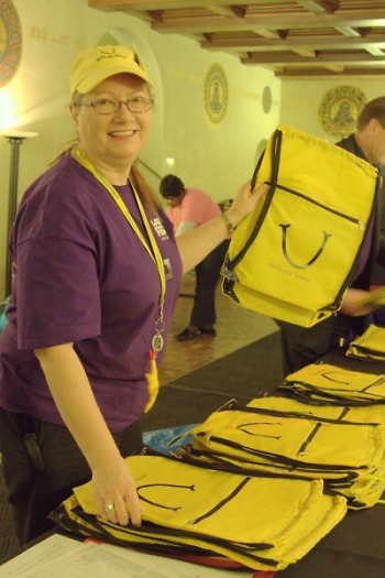 Volunteer Ann Videtich from Kalamazooon shows off one of the LaughFest bags for purchase.
