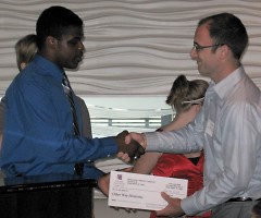 R.J. Ferrell-Tillman presents a check to Kyle Van Strien from The Other Way Ministries.